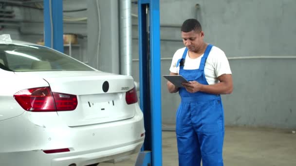 Mechanic examines a car and takes notes — ストック動画