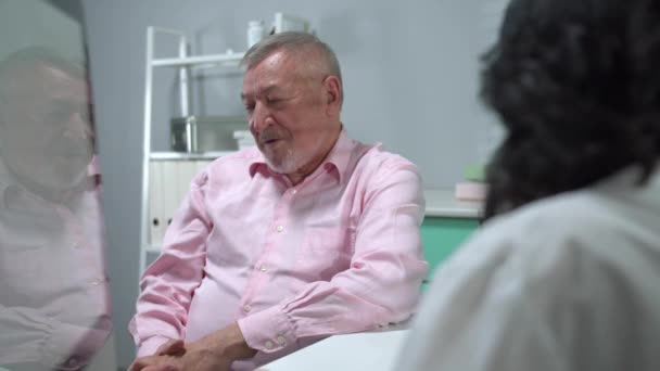 Anciano sentarse en el gabinete del hospital y hablar con el médico — Vídeos de Stock