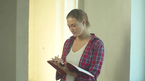 Kvinna står med en anteckningsbok och skriver i den — Stockfoto