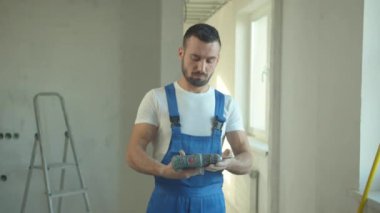 İnşaatçı duruyor ve tornavidaya bakıyor.