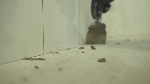 Закрывается, строитель сидит и чистит плитку на стене — стоковое видео