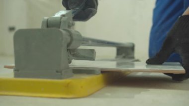 Yavaş çekim, koruyucu eldivenli adam fayans kesiyor.