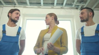 Elinde entrika olan kadın tamircilerle konuşur. 