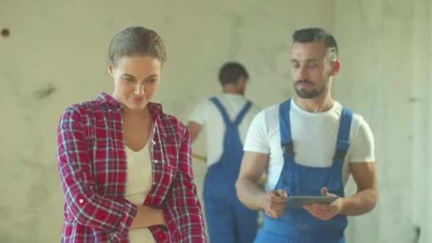 Mulher feliz fala sobre apartamento com construtor — Vídeo de Stock