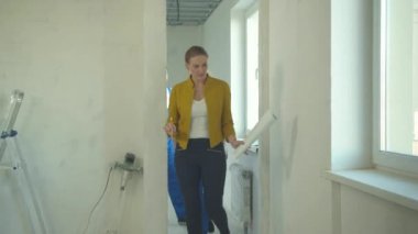 Elinde entrika olan bir kadın tamirciye bir daire gösteriyor.