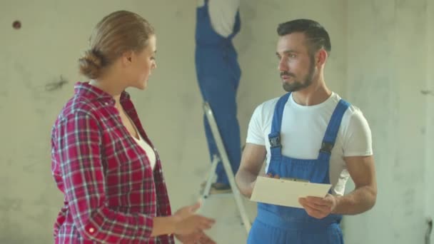 Builder talks with woman and gives her documents — Stock Video