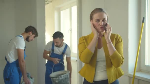 Женщина разговаривает по телефону, строители в униформе — стоковое видео
