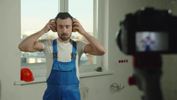 Építő felteszi a fejhallgató és beszél a kamera — Stock videók