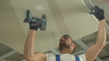 Üniformalı müteahhit tavana bir panel bağlıyor 
