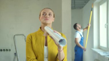 Çizimi olan kadın düşünür, inşaatçı arka planda çalışır.