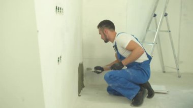 İnşaatçı oturur ve karışımı duvara koyar.