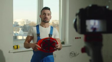 Miğferini çıkarıp kameraya konuşuyor.