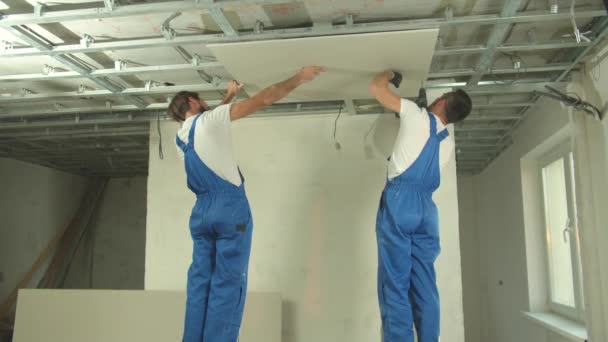 Dois construtores em uniforme instalar o painel no teto — Vídeo de Stock