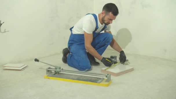 Builder in protective gloves measures a length of a tile — Stock Video