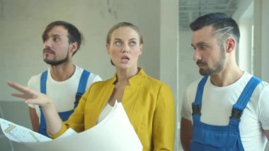 Kadın durumu izah eder ve tamircilere bir iş planı gösterir. 