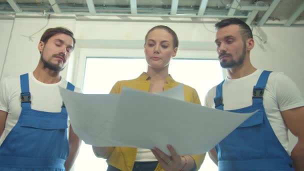 Constructores de pie y escuchar a la mujer con un dibujo — Vídeo de stock