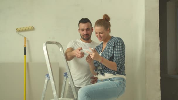 Семейная пара смотрит на фото на телефоне во время ремонта — стоковое видео