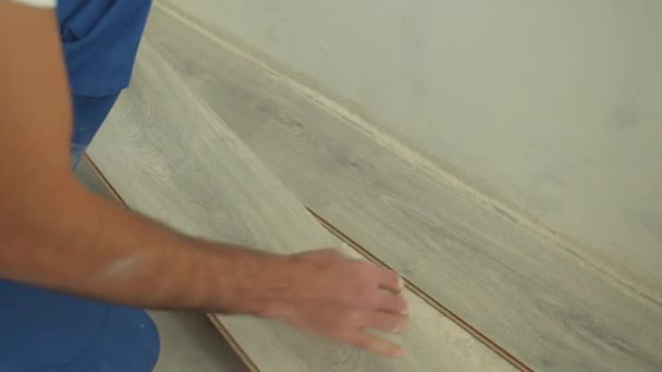 Närbild, byggare i uniform sätter laminat på golvet — Stockvideo