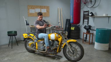 Man sits on a motorcycle and looks in its mirrors 