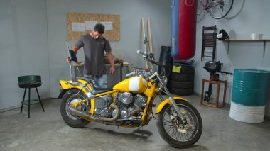 Man goes around a motorcycle and looks at it 