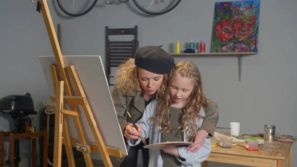 Женщина и девушка рисуют вместе на холсте — стоковое фото