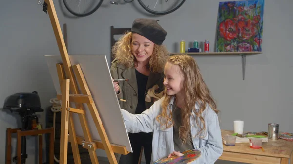 Счастливая девушка и женщина рисуют картину — стоковое фото