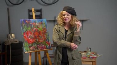Painter stands on the background of her picture and smiles