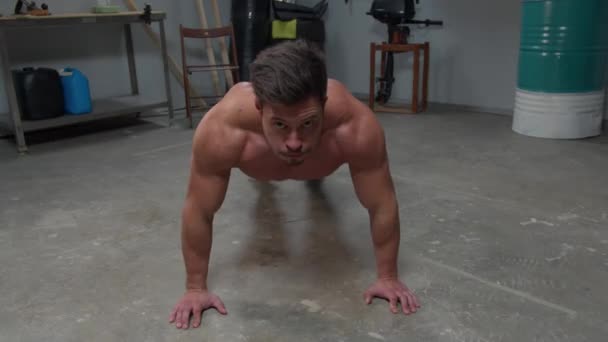 Man without a T-shirt does push-ups on the floor — ストック動画