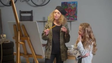 Artist teaches girl to draw on canvas
