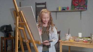 Happy girl draws a picture in the studio
