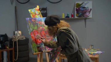 Professional artist paints flowers on canvas