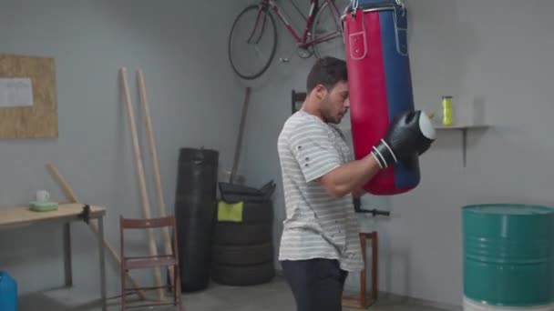 Tired man holds a punching bag in gym — Αρχείο Βίντεο