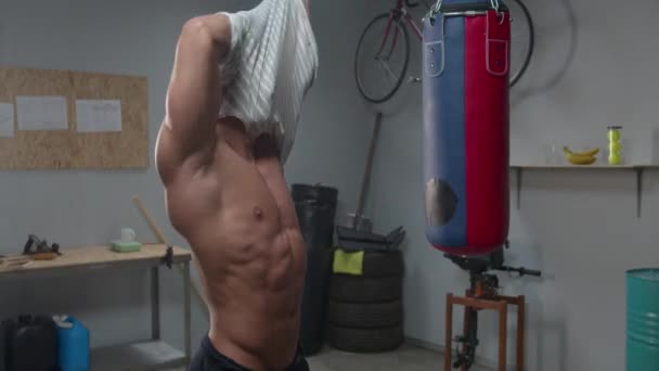 Man puts off his shirt in the gym — Stockvideo