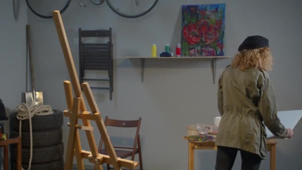 Woman puts a canvas on an easel — Stockvideo