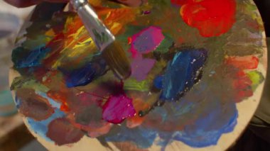 Woman mixes paints on the art palette