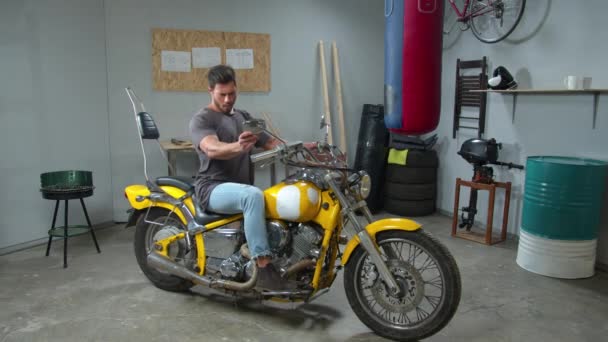 Man sits on a motorcycle and looks in its mirrors — 图库视频影像