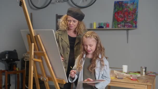 Woman controls the drawing process of a girl — Stockvideo