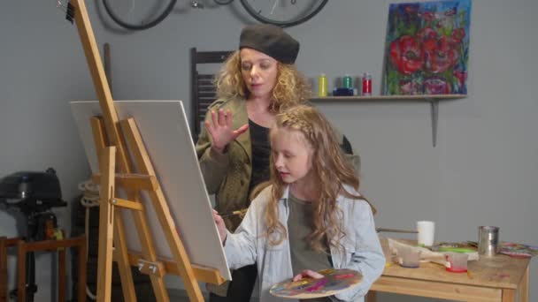 Художник учит девочку рисовать красками — стоковое видео