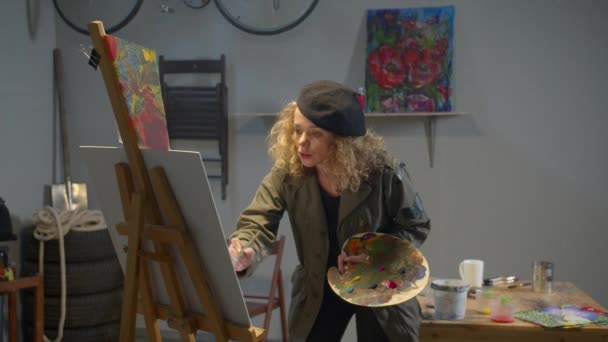 Woman with paints redraws picture in studio — Αρχείο Βίντεο