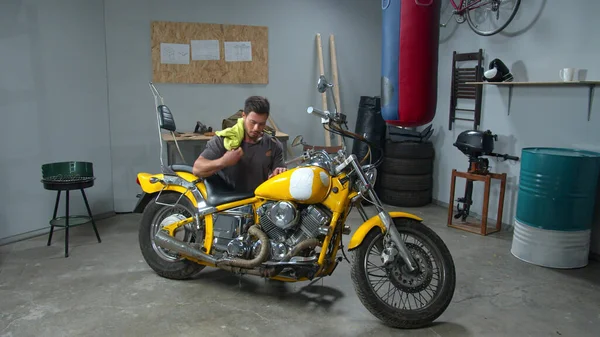 Seorang pria menyeka sepeda motor dengan kain di garasi — Stok Foto