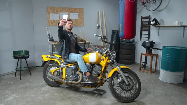 Man in leren jas maakt foto met een motorfiets — Stockfoto