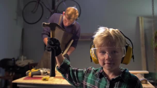 Мальчик в очках стоит с молотком и смотрит в камеру, замедленная съемка — стоковое видео