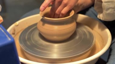 Kadın bir atölyede çömlek çarkına çömlek yapıyor, ağır çekimde.