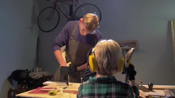 El hombre trabaja con madera y el chico lo mira — Vídeos de Stock