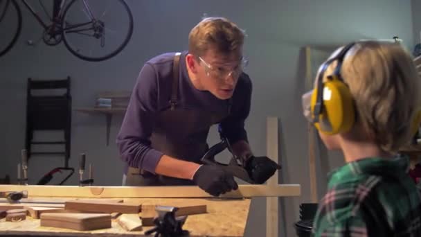 Master shows to boy how work with wood — Stock Video