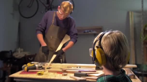 Ragazzo guarda l'uomo che lavora in officina — Video Stock