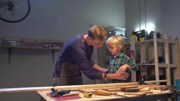 Man puts boy on the board in the workshop — Stock Video