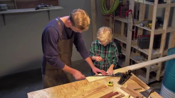 Trabajo de hombre y niño con tabla de madera en el taller — Vídeos de Stock