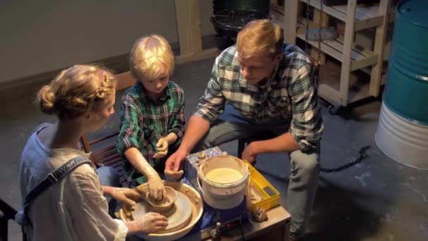 Movimento lento, mulher ensina homem e menino a trabalhar com roda de cerâmica — Vídeo de Stock