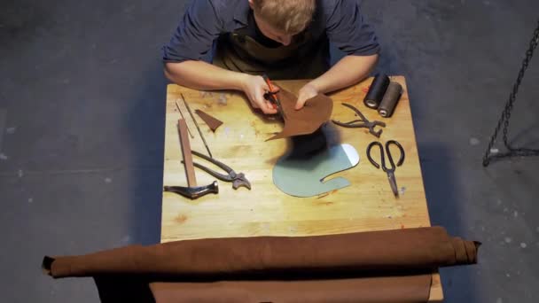 Homme coupe un morceau de tissu pour chaussures dans un atelier — Video